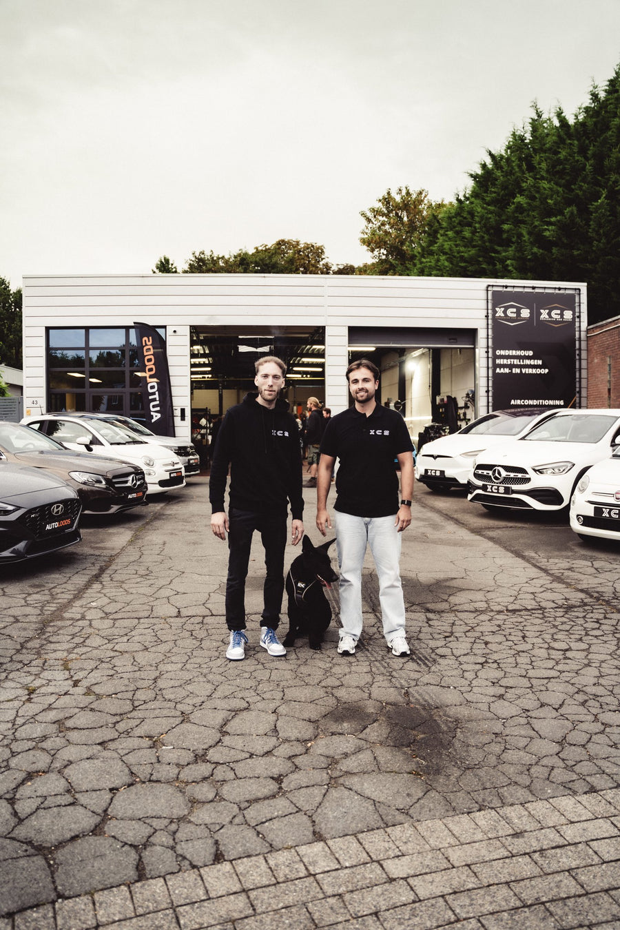 Quinten en Jorne met hun hond voor de garage van XCS Automotive in Merchtem