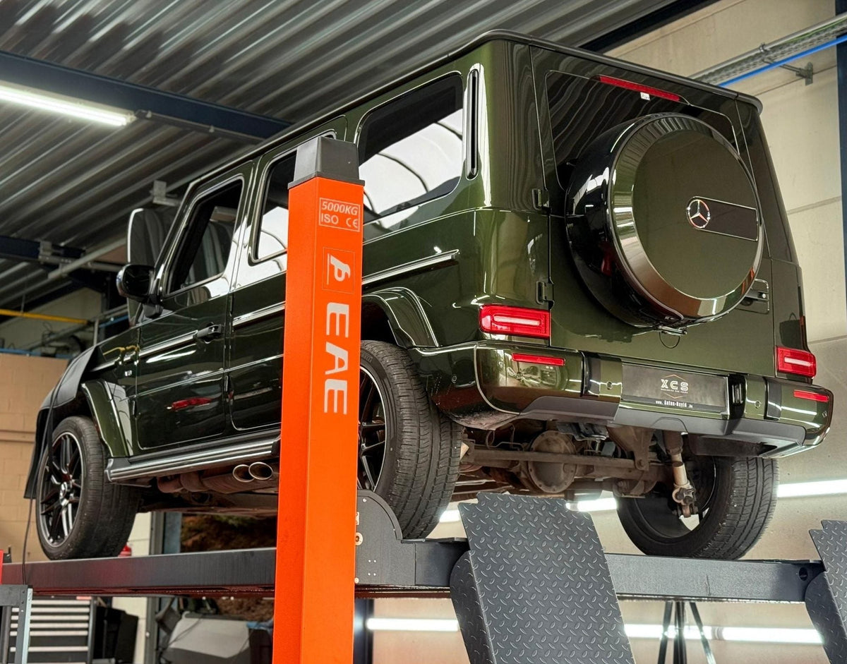 Groene Mercedes G-Klasse op de brug voor een nazicht vóór de keuring in de werkplaats van XCS Automotive in Merchtem