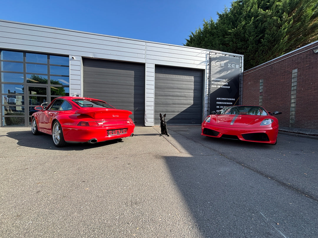 Garage XCS Automotive in Merchtem met een rode Porsche 911 en een rode Ferrari voor de deur