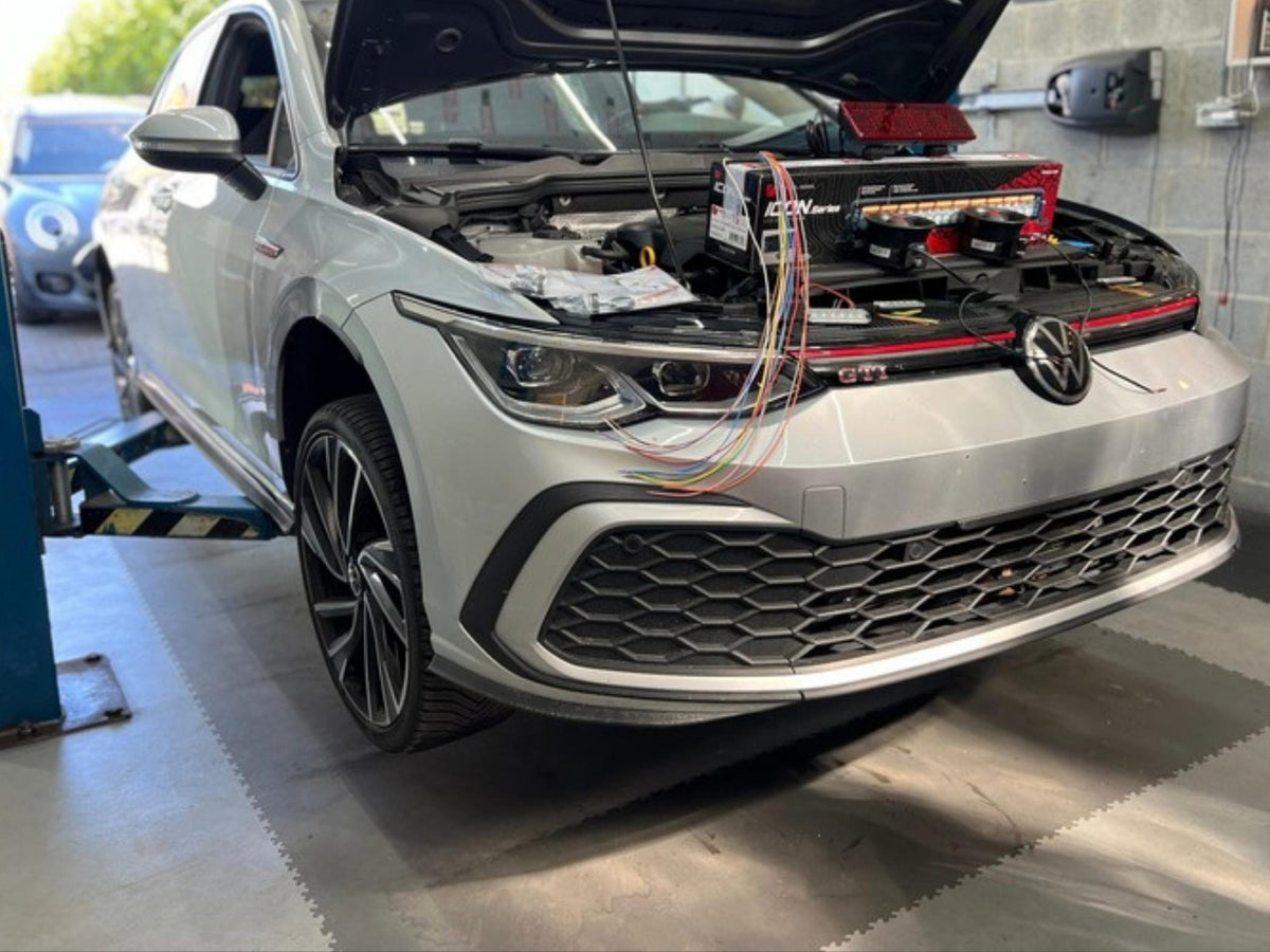 Witte Volkswagen Golf 8 met open motorkap in de werkplaats van XCS Automotive in Merchtem