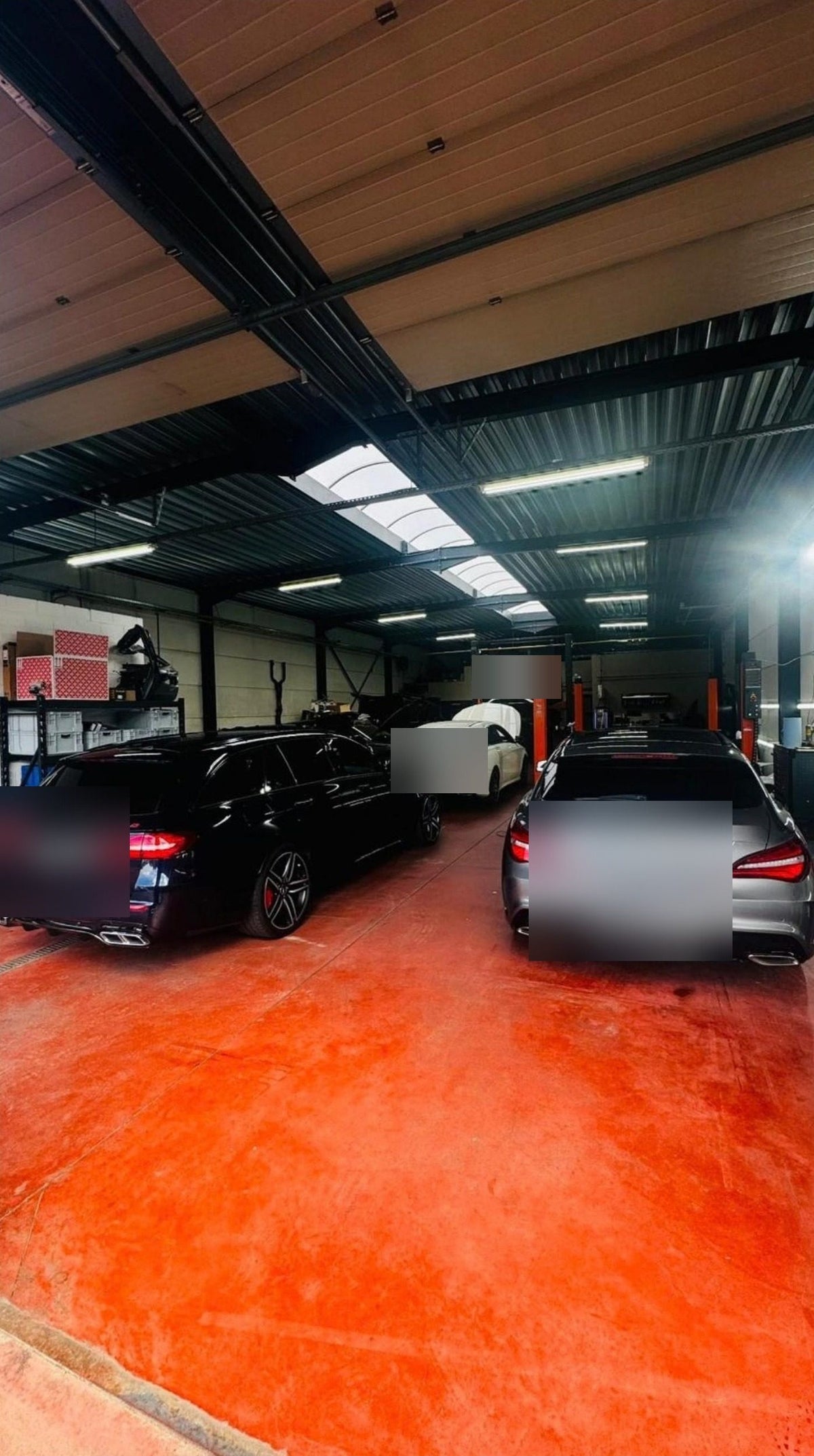 Werkplaats met rode vloer en wagens bij XCS Automotive in Merchtem