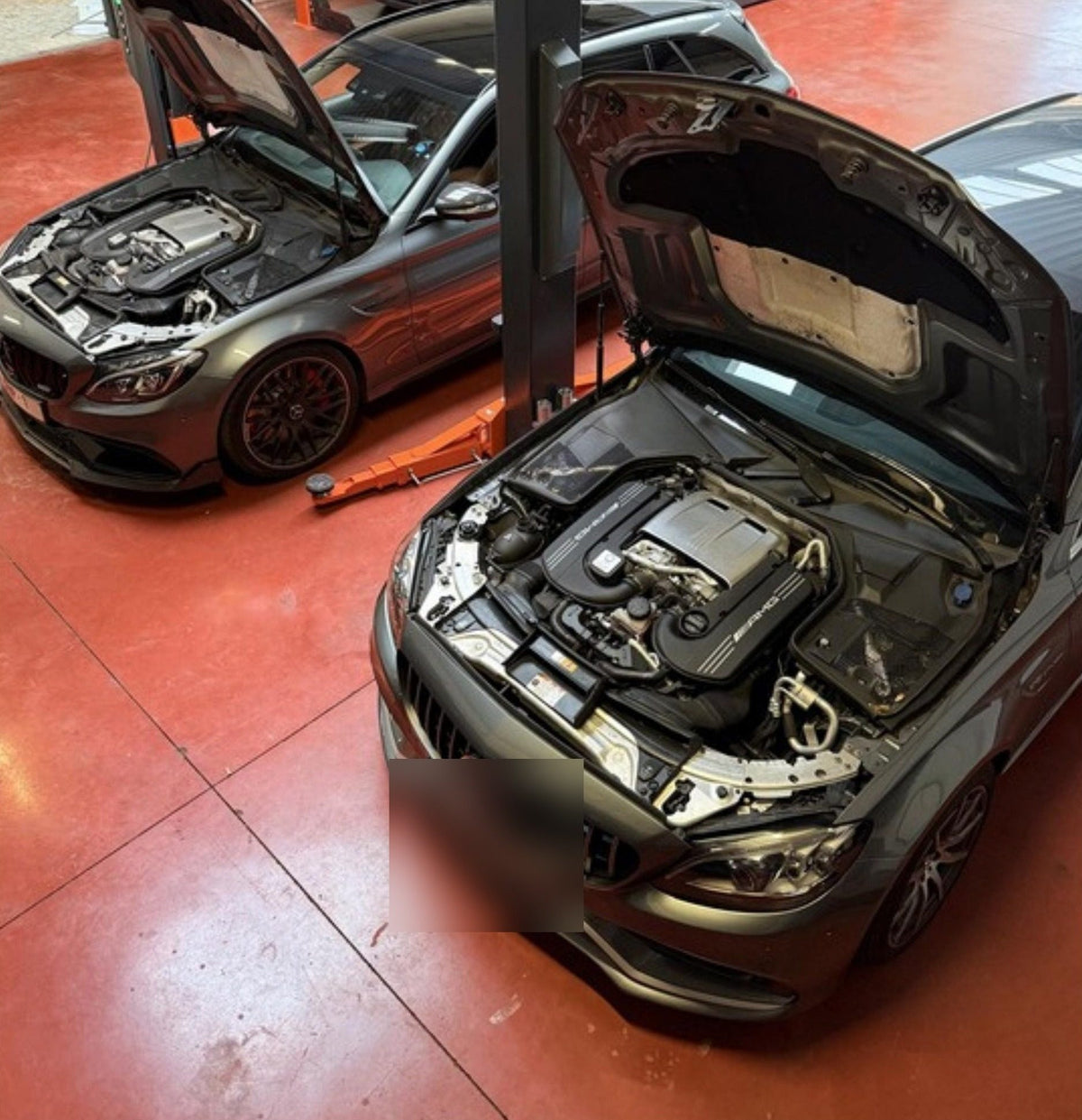 Twee Mercedes-AMG C63 met open motorkap in de werkplaats van XCS Automotive in Merchtem