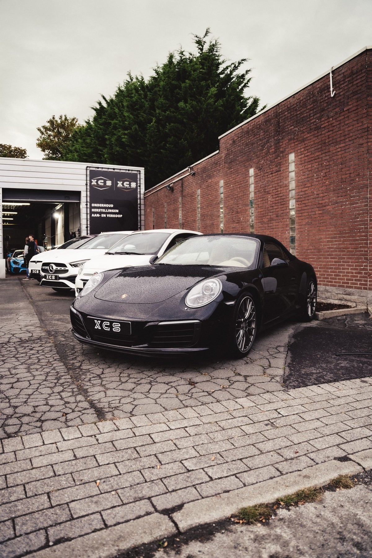 Huidig aanbod bij XCS Automotive: zwarte Porsche 911 Cabriolet en Mercedes-Benz wagens voor de garage