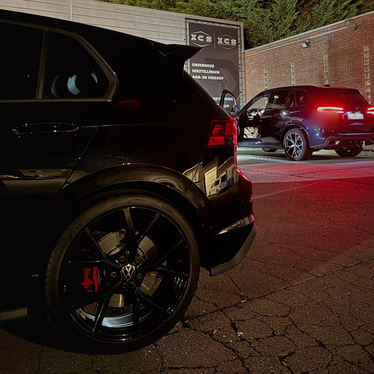 Zwarte SUV ’s avonds voor het verlichte gebouw van XCS Automotive